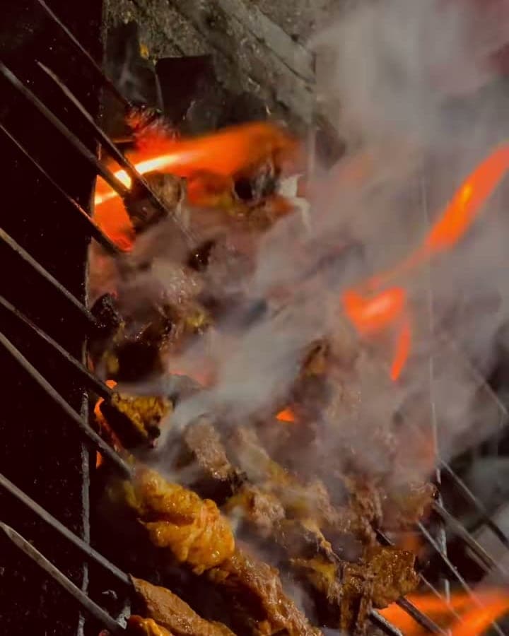 Köttspett som grillas över öppen eld och glöd